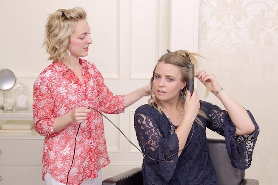 Stylist and client using a flat iron to get curls