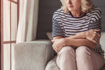 Woman sitting by window, feeling sad or afraid