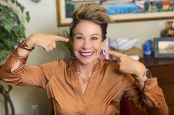 Carol smiling pointing to her face